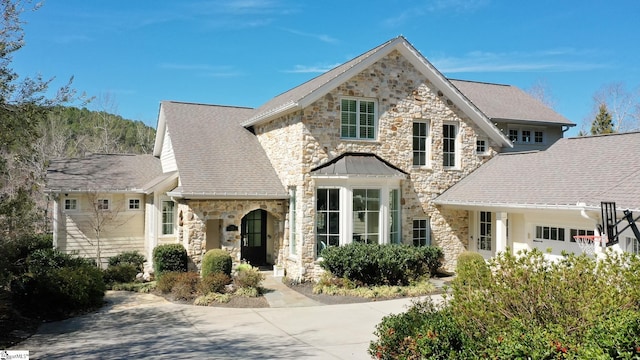 view of front facade with stone siding and roof with shingles