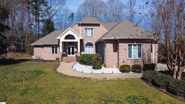 view of front of home with french doors, brick siding, a front lawn, and roof with shingles