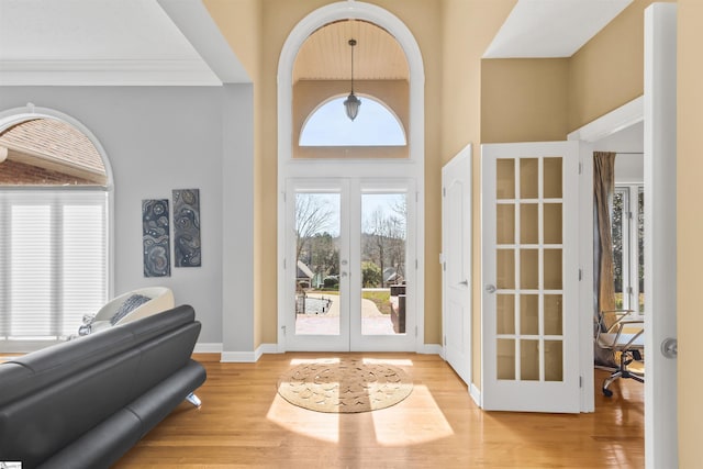 entrance foyer with french doors, a high ceiling, baseboards, and wood finished floors