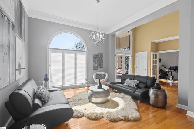 living room with an inviting chandelier, a wealth of natural light, wood finished floors, and french doors