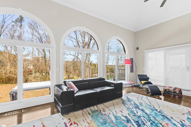 interior space featuring ceiling fan, visible vents, wood finished floors, and ornamental molding