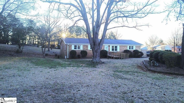 single story home with brick siding, a wooden deck, and a front yard