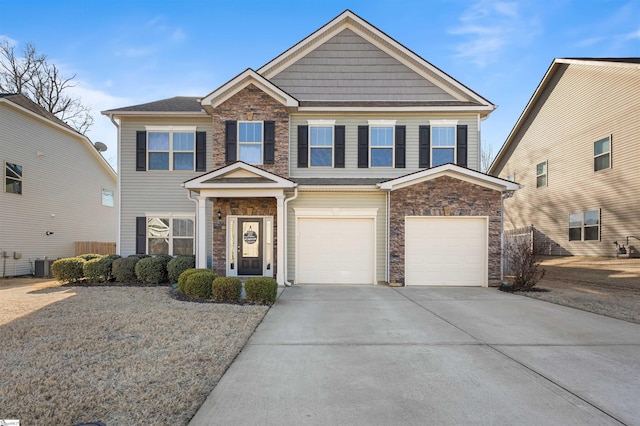 view of front of property with a garage, stone siding, central AC, and driveway