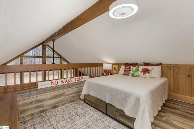 bedroom with wooden walls, lofted ceiling with beams, and wood finished floors