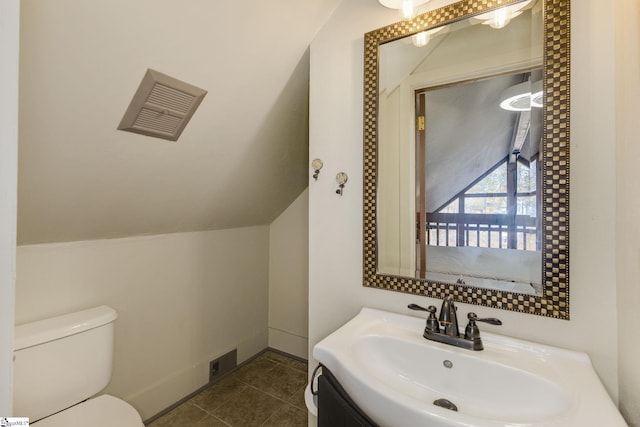 half bath with visible vents, toilet, vaulted ceiling, vanity, and tile patterned floors