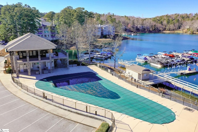 community pool featuring a patio area, fence, and a water view