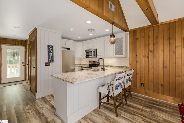 kitchen featuring light wood finished floors, visible vents, appliances with stainless steel finishes, white cabinets, and a peninsula