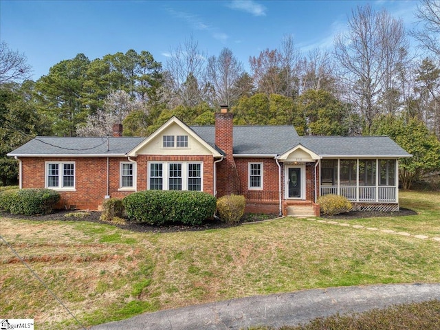 ranch-style house with brick siding, a chimney, and a front yard