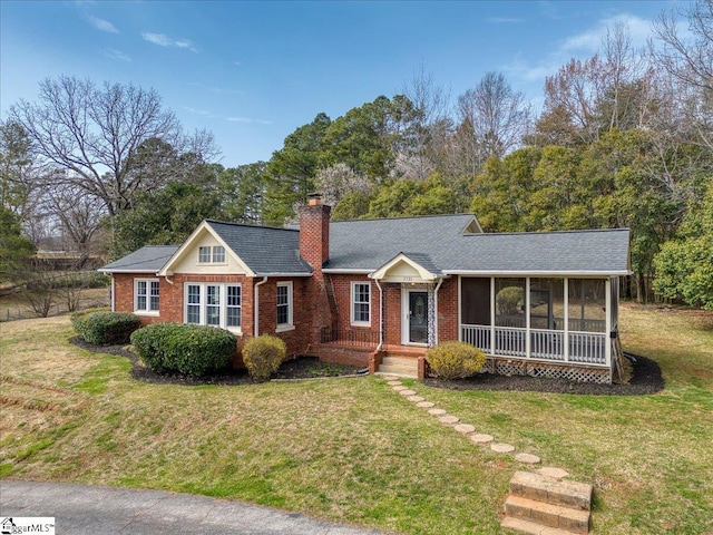 single story home with brick siding, a sunroom, roof with shingles, a chimney, and a front yard