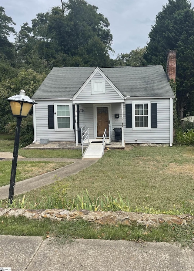 bungalow-style home with a shingled roof, a chimney, crawl space, covered porch, and a front yard