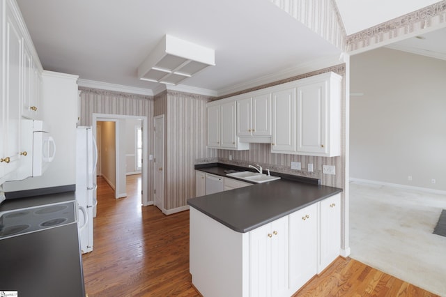 kitchen with dark countertops, white appliances, white cabinetry, and crown molding