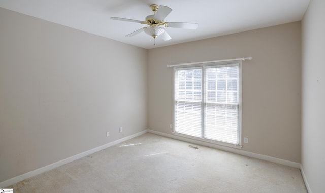 spare room with baseboards, ceiling fan, visible vents, and light colored carpet