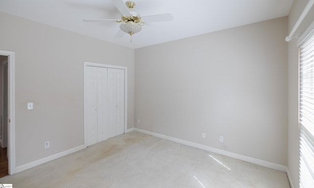 unfurnished bedroom featuring light carpet, a closet, a ceiling fan, and baseboards