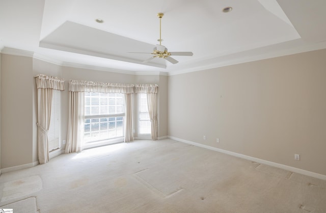 spare room featuring a tray ceiling, light carpet, and baseboards