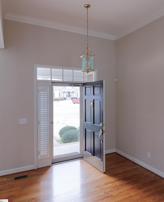 foyer featuring baseboards, wood finished floors, visible vents, and crown molding