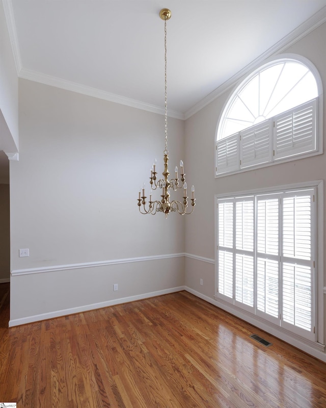 empty room featuring ornamental molding, visible vents, and wood finished floors