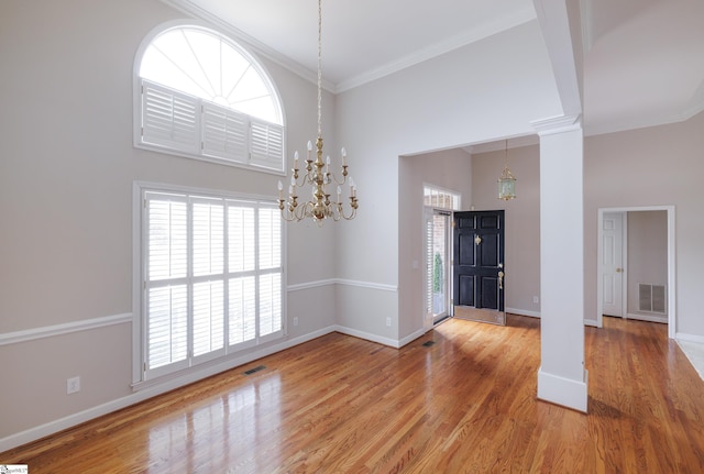 interior space with light wood-style floors, ornate columns, visible vents, and a high ceiling