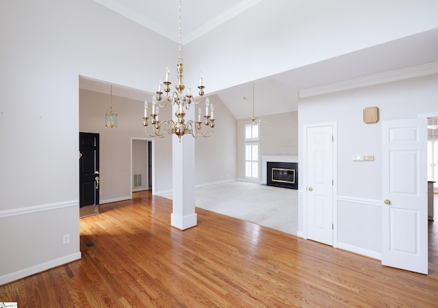 interior space featuring visible vents, a fireplace with flush hearth, wood finished floors, high vaulted ceiling, and baseboards