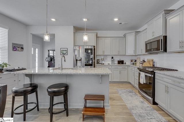 kitchen with a breakfast bar, tasteful backsplash, visible vents, appliances with stainless steel finishes, and a sink