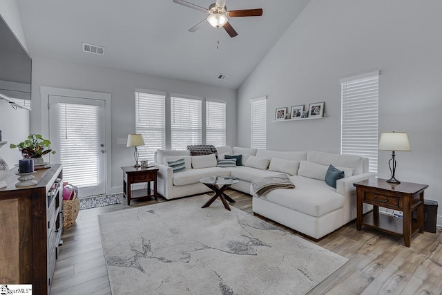 living area featuring a ceiling fan, visible vents, high vaulted ceiling, and light wood finished floors