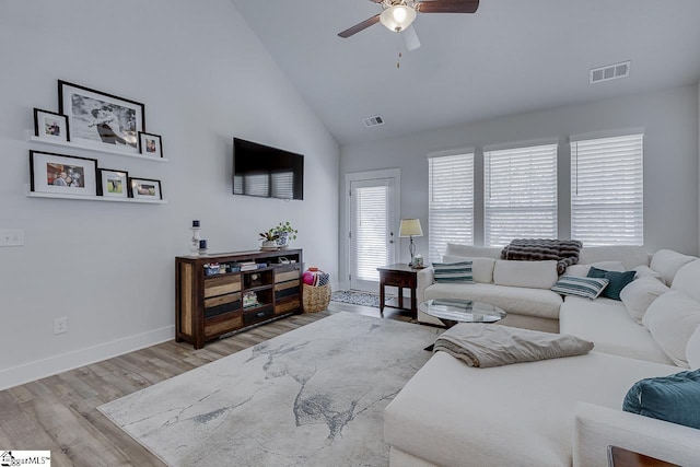 living room with baseboards, high vaulted ceiling, visible vents, and light wood-style floors