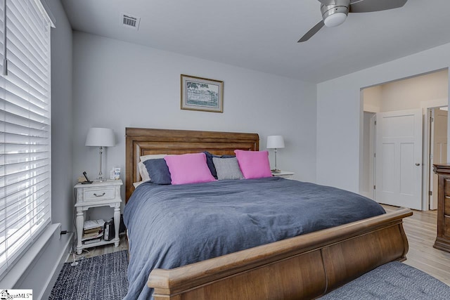 bedroom with ceiling fan, visible vents, and wood finished floors