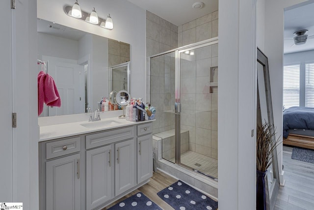 ensuite bathroom with visible vents, ensuite bath, wood finished floors, vanity, and a shower stall