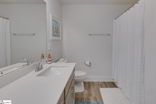 bathroom featuring baseboards, vanity, toilet, and wood finished floors