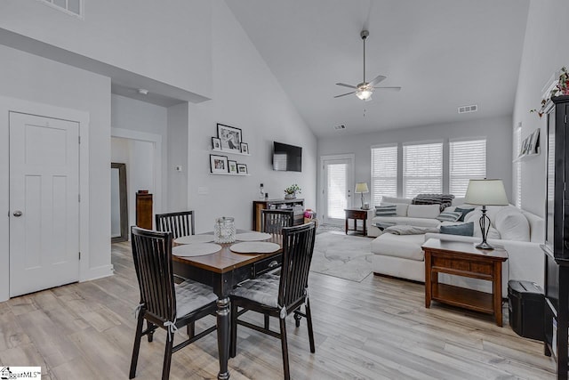 dining space featuring light wood-style floors, visible vents, and high vaulted ceiling