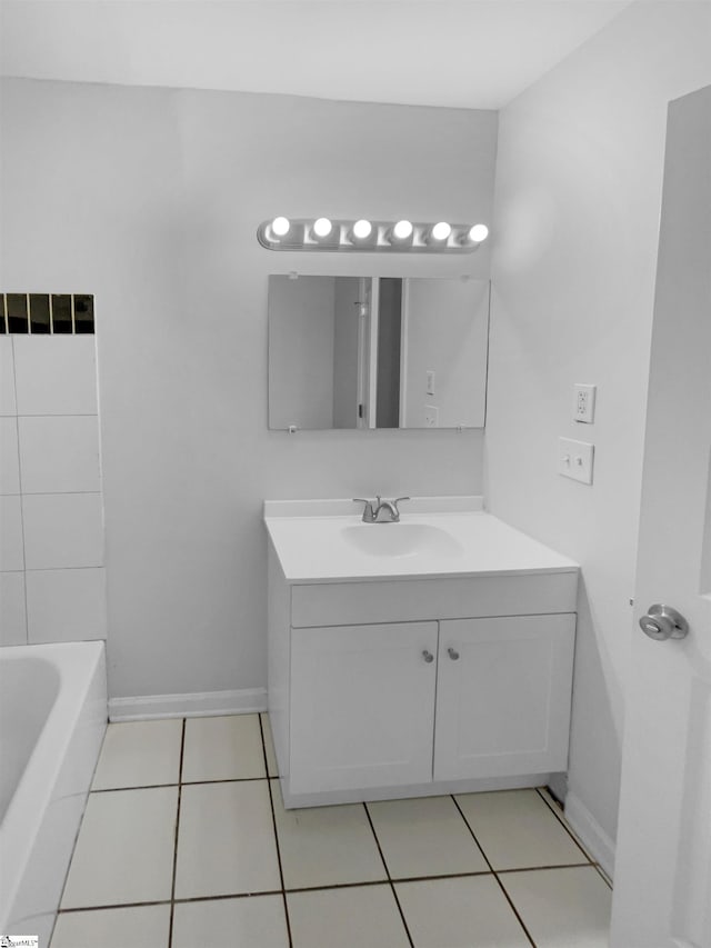 bathroom featuring tile patterned floors, baseboards, vanity, and a washtub