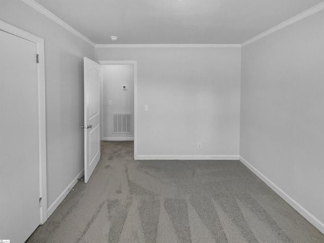 carpeted spare room with visible vents, baseboards, and crown molding