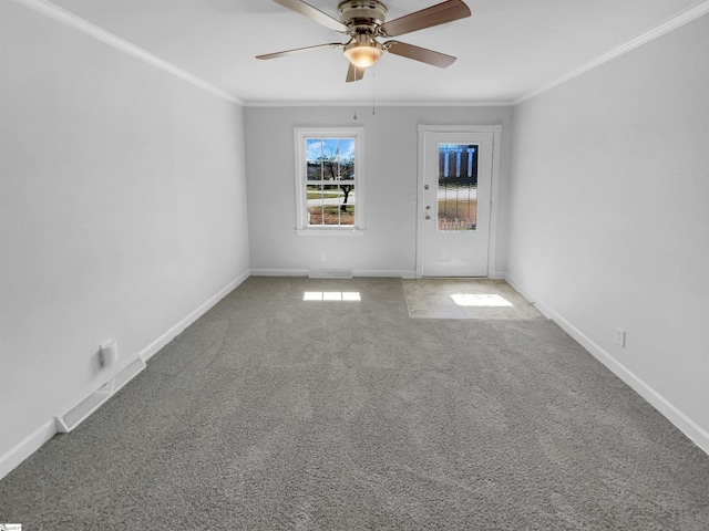 carpeted spare room with visible vents, baseboards, ornamental molding, and a ceiling fan