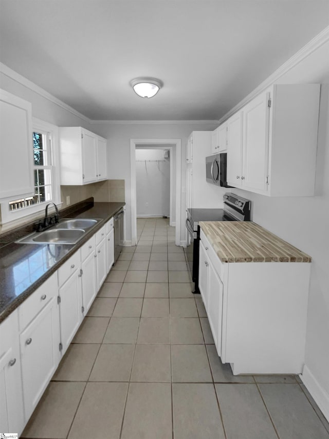 kitchen with ornamental molding, a sink, white cabinetry, stainless steel appliances, and light tile patterned floors