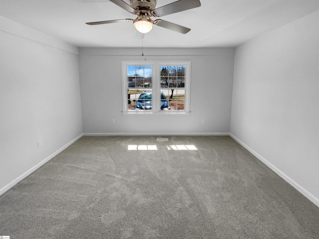 carpeted spare room featuring a ceiling fan and baseboards