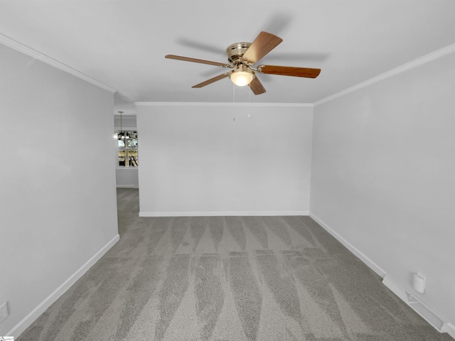 carpeted spare room featuring ceiling fan, baseboards, and ornamental molding