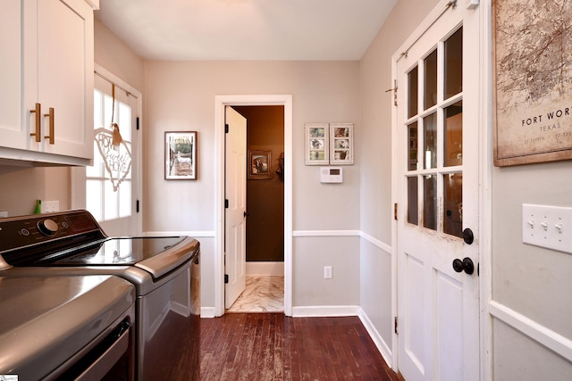 laundry room with cabinet space, baseboards, dark wood-type flooring, and washer and dryer