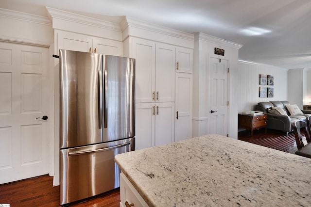 kitchen with light stone countertops, crown molding, dark wood-type flooring, and freestanding refrigerator