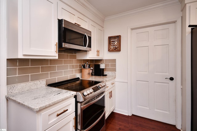 kitchen featuring dark wood finished floors, stainless steel appliances, backsplash, ornamental molding, and white cabinets