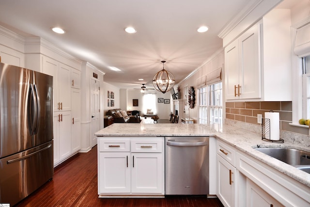 kitchen featuring a peninsula, white cabinets, open floor plan, appliances with stainless steel finishes, and dark wood finished floors