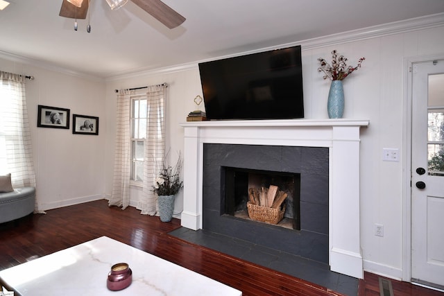 living room featuring baseboards, a tiled fireplace, ceiling fan, hardwood / wood-style floors, and crown molding