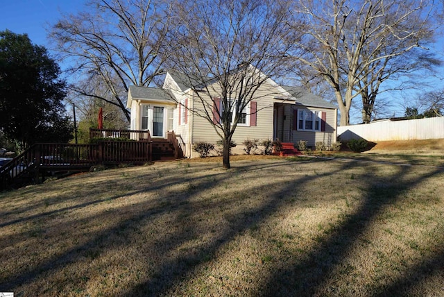 view of front of property with a deck, a front yard, and fence