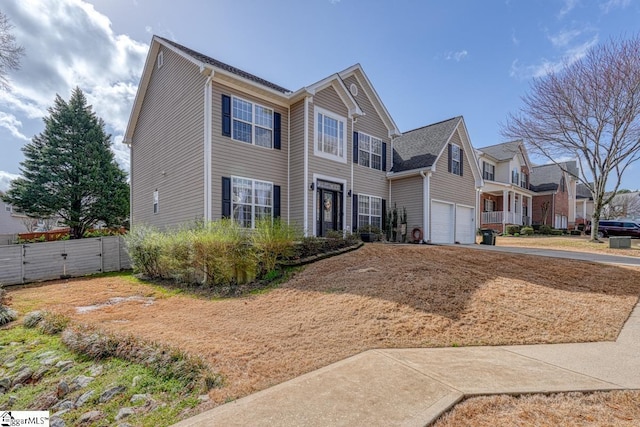 traditional-style home featuring a residential view, driveway, an attached garage, and fence