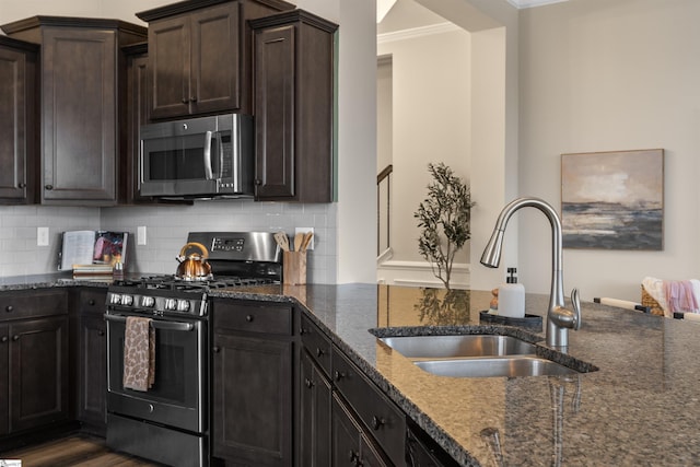 kitchen featuring a sink, backsplash, dark stone counters, appliances with stainless steel finishes, and dark brown cabinets