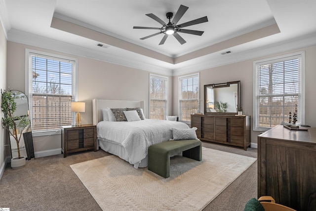 bedroom with a tray ceiling, visible vents, and carpet floors