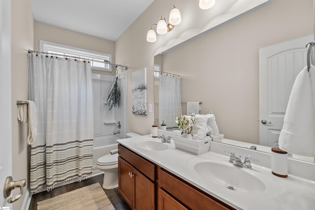 bathroom featuring double vanity, shower / bath combination with curtain, toilet, and a sink