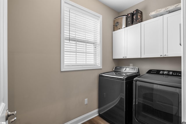 clothes washing area with cabinet space, washing machine and dryer, baseboards, and dark wood-type flooring