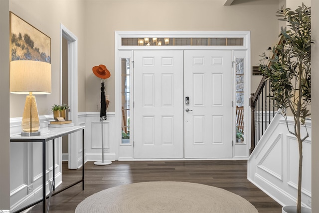 entryway with stairs, wainscoting, dark wood-style flooring, and a decorative wall