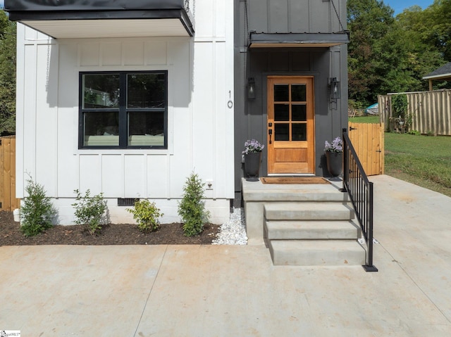 doorway to property with board and batten siding, crawl space, and fence