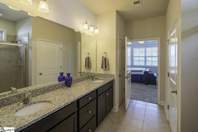 bathroom featuring tile patterned flooring, a stall shower, visible vents, and a sink