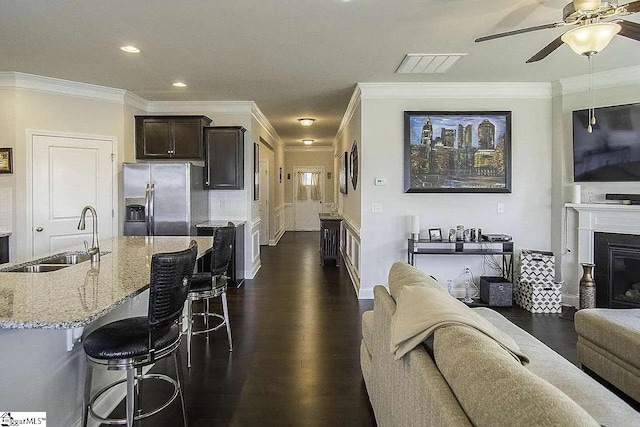 living room featuring a glass covered fireplace, visible vents, dark wood finished floors, and ornamental molding